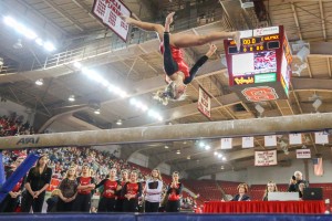 Sophomore Courtney Bisbe does a backflip split on the beam while her team watches. Bisbe scored a 9.675 during the four-school meet on Saturday. The Wolfpack placed third with a 194.050 behind WVU and UNC but ahead of William and Mary on Saturday in Reynolds Coliseum. By: Nick Faulkner