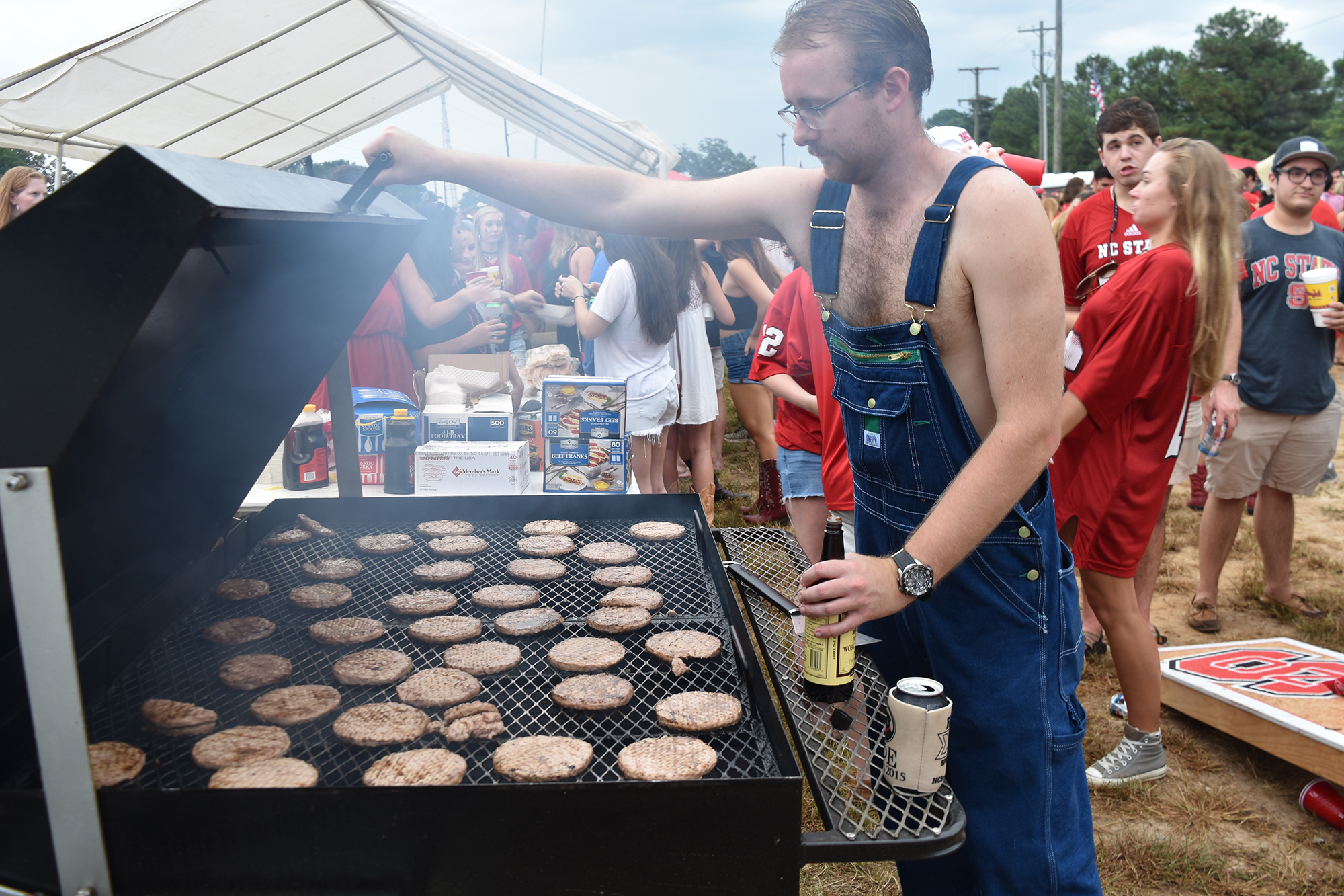 James Stonecypher, a junior in environmental technology and management, grills out at the William and Mary football game held at Carter Finley Stadium on Sept. 1. Stonecypher poured worcestershire sauce on top of the meat to get ready to serve the food.