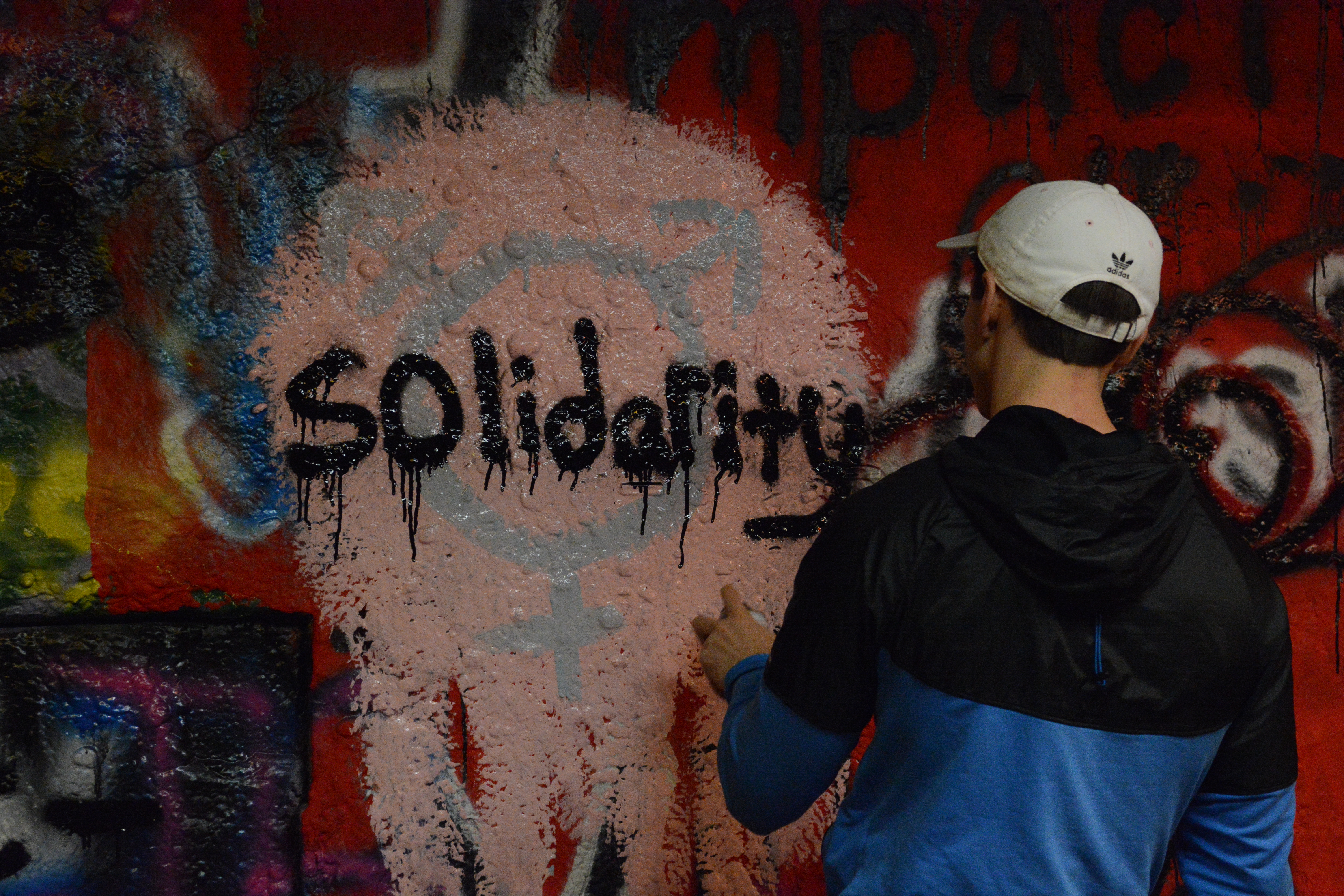 Person spray painting solidarity over transgender symbol